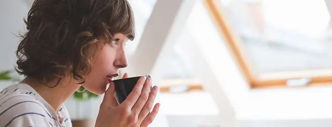 Chica tomándose feliz una taza de café porque tiene la mejor oferta de fibra y móvil Euskaltel